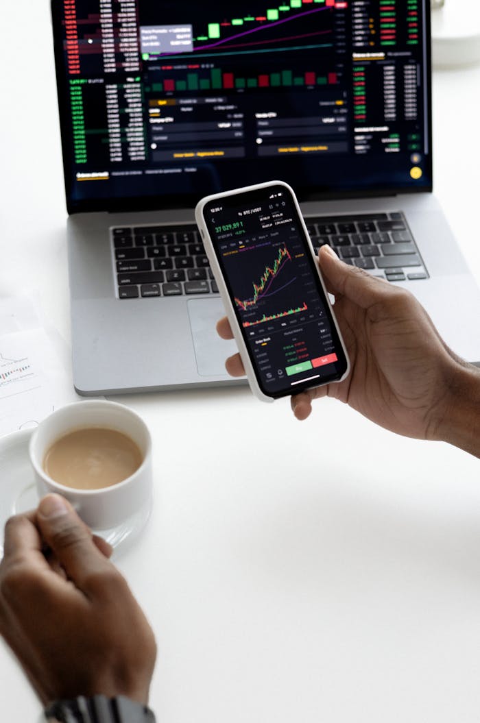 about-01 Person analyzing stock market trends on smartphone with laptop background